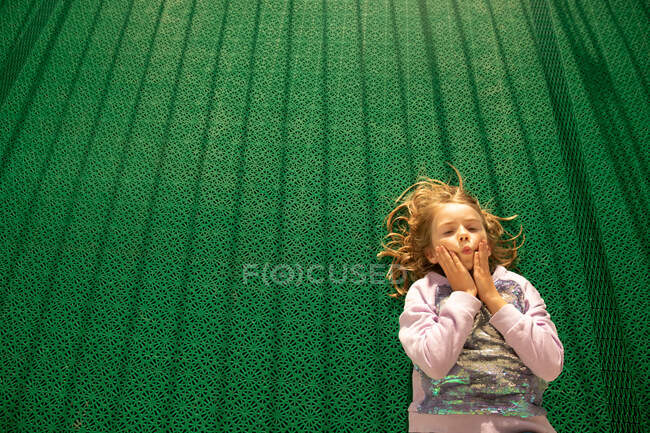 Mädchen liegt mit lustigem Ausdruck auf grünem Boden in Helsinki, Finnland — Stockfoto
