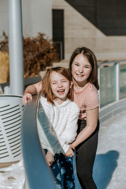 Happy young girls hugging on the side of ice skating rink — Stock Photo