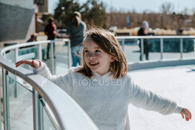 Junges Mädchen hält sich am Geländer fest, während es Eislaufen lernt — Stockfoto