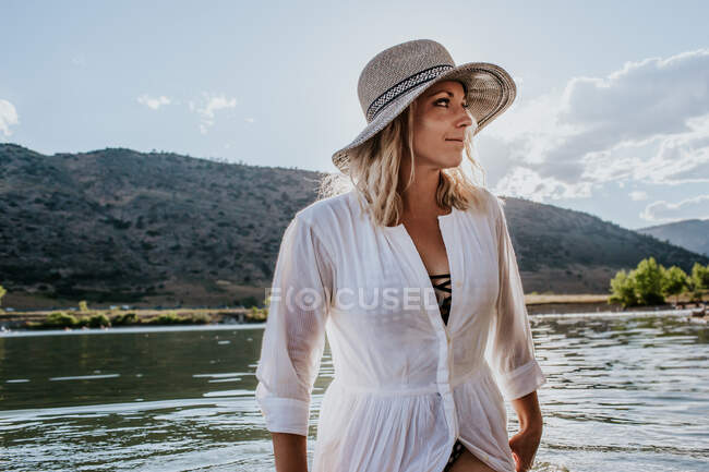 Woman in a dress standing in water looking away on a sunny day — Stock Photo