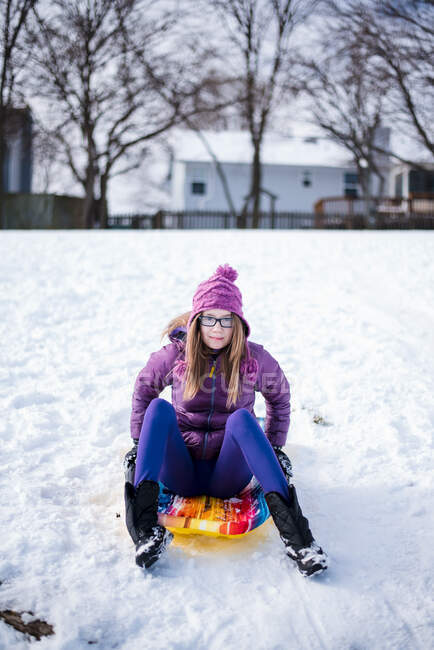 Pre teen sitting on sled in the snow in winter — Stock Photo