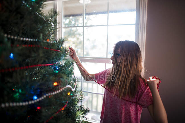 Pre teen girl decorating christmas tree at home — Stock Photo