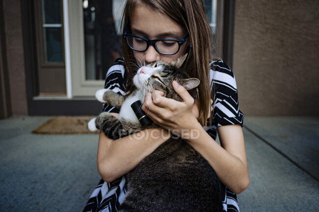 Ein Pre-Teenie-Mädchen küsst ihre Katze auf der Veranda — Stockfoto