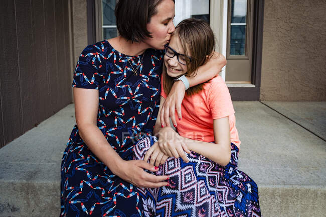 Mamma baciare figlia sul portico anteriore — Foto stock