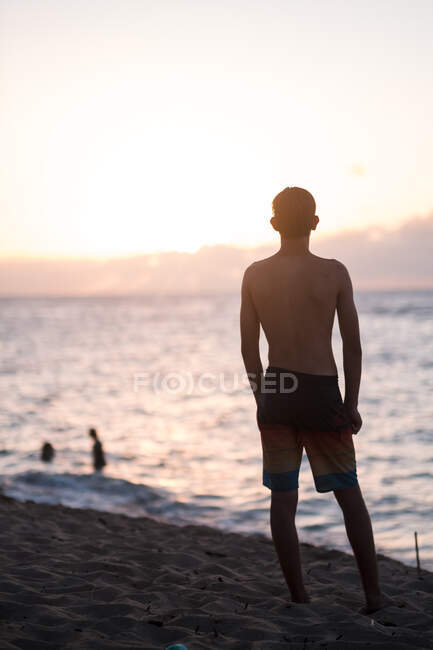 Хлопчик-підліток спостерігає за заходом сонця на північному березі Оаху — стокове фото