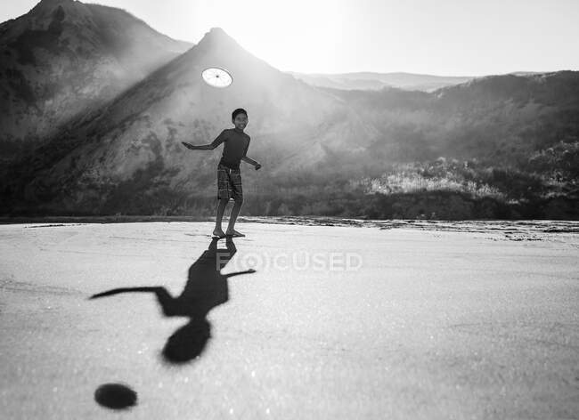 Tween throwing a frisbee on a beach — Stock Photo