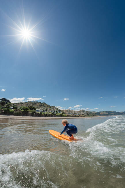 Pequena criança surfando na Nova Zelândia em um dia ensolarado — Fotografia de Stock