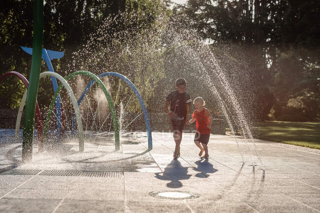 Brothers running in water at playground in New Zealand — Stock Photo