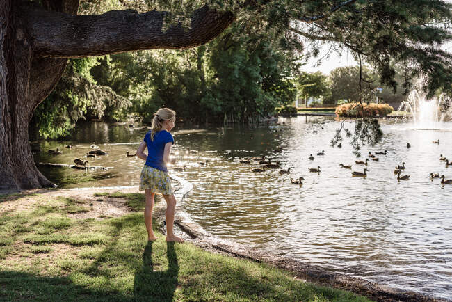 Preteen girl watching ducks in a pond in New Zealand — Stock Photo