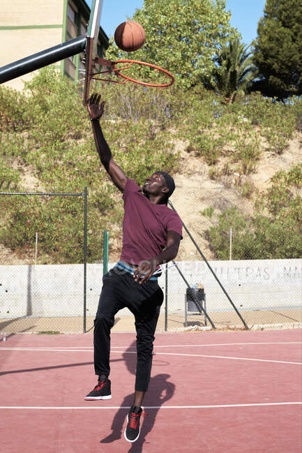Молодой чёрный мужчина стреляет в баскетбол — стоковое фото