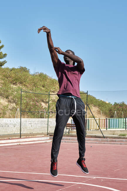 Joven hombre negro lanzando la pelota a la canasta de baloncesto - foto de stock