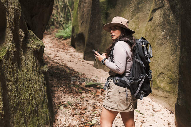 Женщина с GPS и рюкзаком оглядывается назад. — стоковое фото