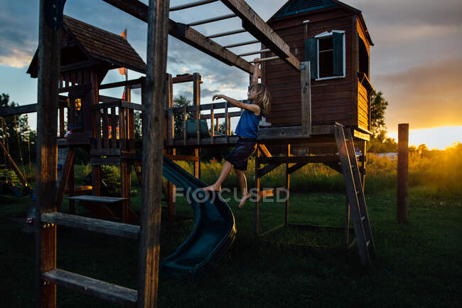 Young boy on play center at sunset — Stock Photo