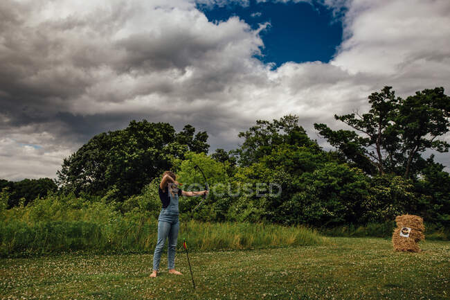 Girl shooting compound bow in open field — Stock Photo