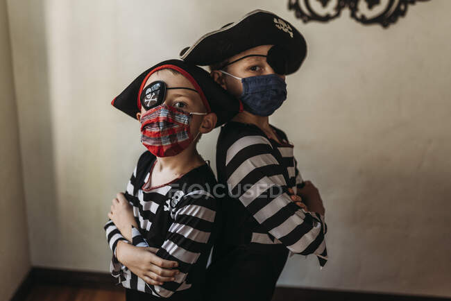 Hermanos en edad escolar vestidos de piratas con máscaras en la cara - foto de stock