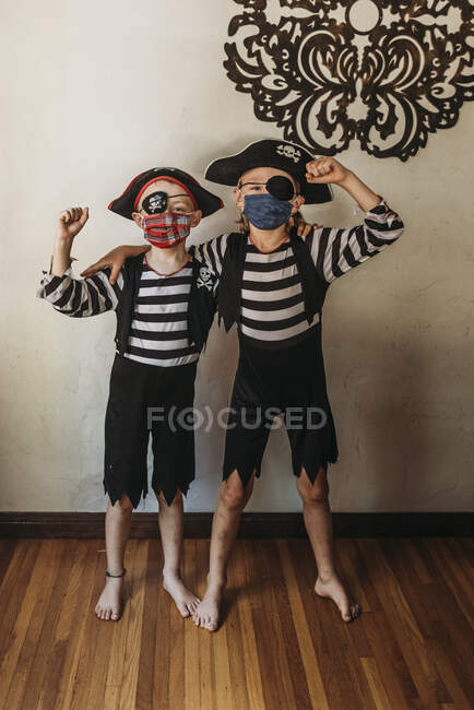 Fratelli in età scolare vestiti da pirati con maschere facciali a casa — Foto stock