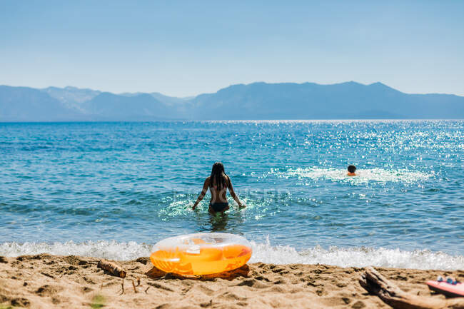 Nadando en un lago de montaña con cielos azules y un inflable naranja - foto de stock