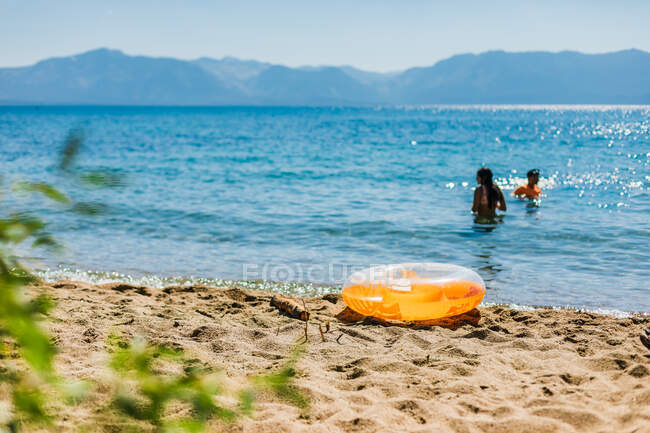 Nager dans un lac de montagne bleu avec un gonflable orange — Photo de stock
