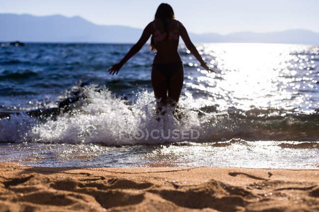 Плавець стоїть у хвилях з водою, що топить озеро на горі — стокове фото