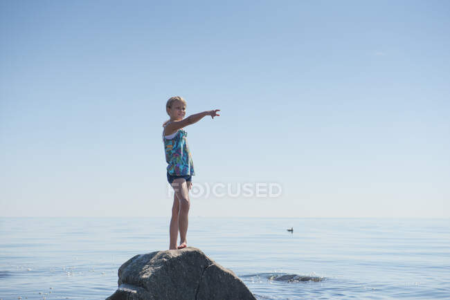 Jeune fille debout sur le rocher par l'océan — Photo de stock