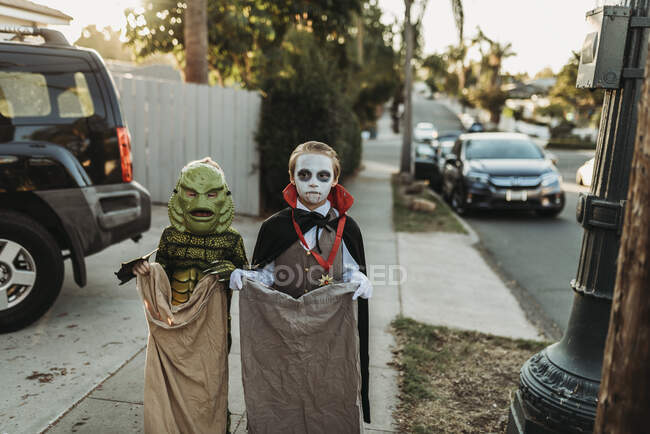 Jeunes frères et sœurs habillés en costumes d'Halloween pendant Trick-or-Treat — Photo de stock