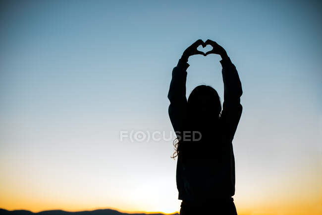 As mãos formam uma silhueta de coração para o amor com pôr do sol ou nascer do sol — Fotografia de Stock