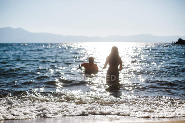 Nuotatori in un lago blu con sole e sabbia per fughe in montagna — Foto stock