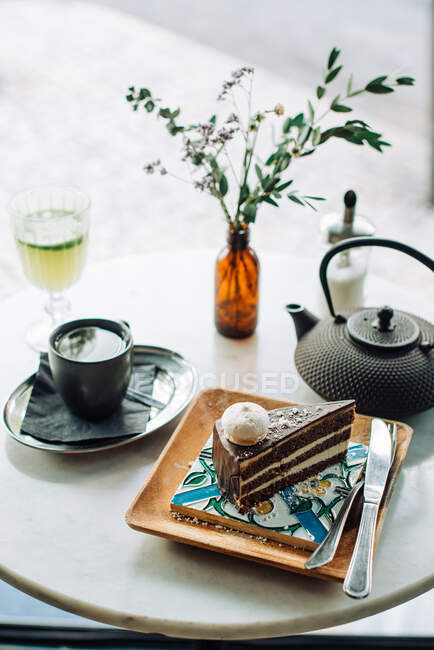 Chocolate cake with cream cheese and coffee on white table with cup of tea — Stock Photo