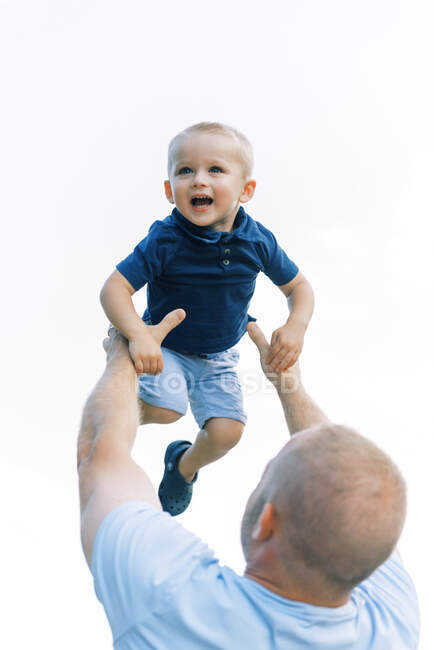 A father throwing his son into the air during playtime outside — Stock Photo