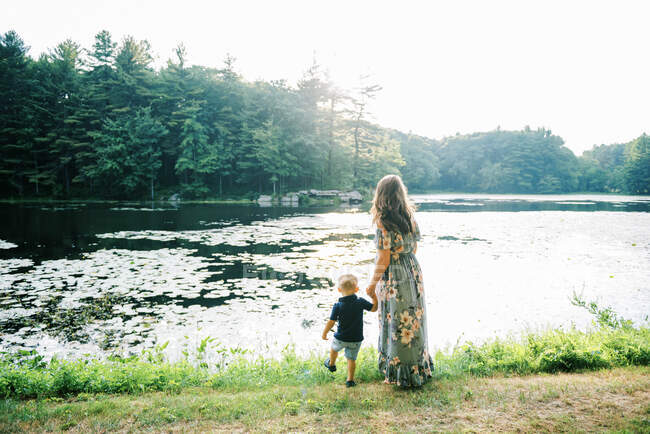 Мать с сыном смотрят, как солнце садится над озером — стоковое фото