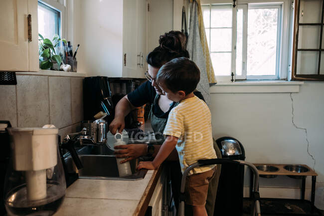 Мать и ребенок работают вместе на кухне раковина — стоковое фото