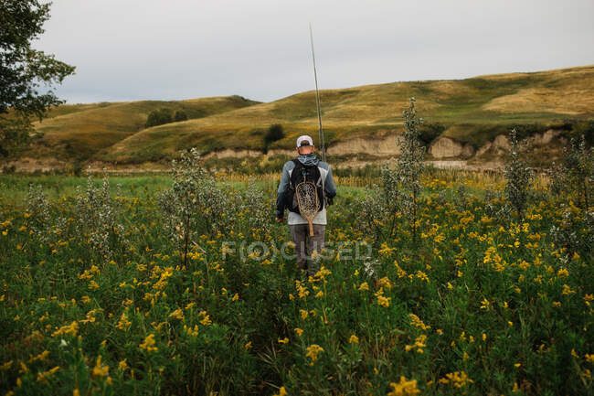 Человек ходит по высокой траве к рыбе — стоковое фото
