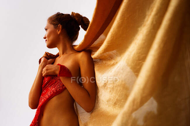 Молодая загорелая голая женщина завернута в золотой занавес снаружи. — стоковое фото
