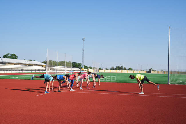 Frauengruppe übt Pre-Workout-Stretching mit ihrem jungen Trainer — Stockfoto