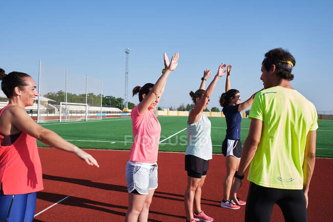 Frauengruppe übt Pre-Workout-Stretching mit ihrem jungen Trainer — Stockfoto