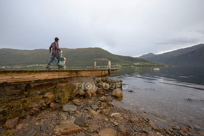 A Norwegian man with  crab pots near the fjord — Stock Photo