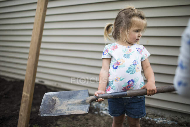 Niña ayudando a los padres con el proyecto de patio trasero - foto de stock