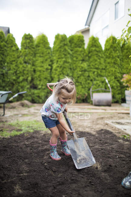 Bambina aiutare i genitori con progetto cortile — Foto stock