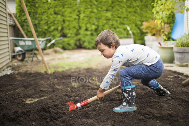 Pequeño niño ayudando a los padres con el proyecto de patio trasero - foto de stock