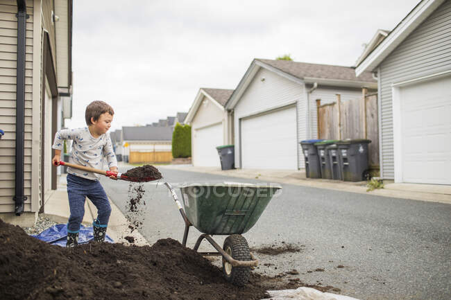Petit garçon aider les parents avec le projet arrière-cour — Photo de stock
