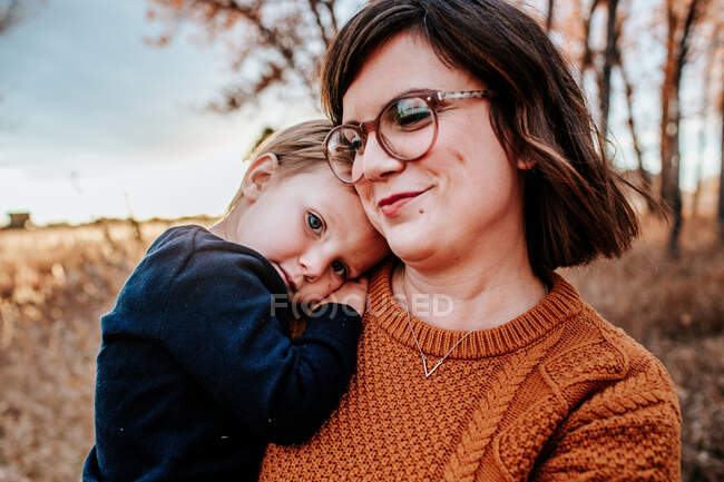 Zufriedener Kleinkind umarmt seine lächelnde Mutter draußen an einem Herbstabend — Stockfoto