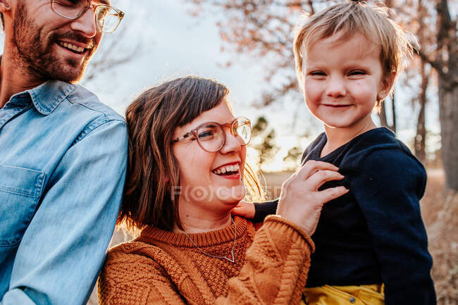 Sorridente genitori solletico giovane figlio fuori in una sera d'autunno — Foto stock