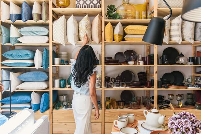 Femme naviguant oreillers et textiles à la boutique home goods store — Photo de stock