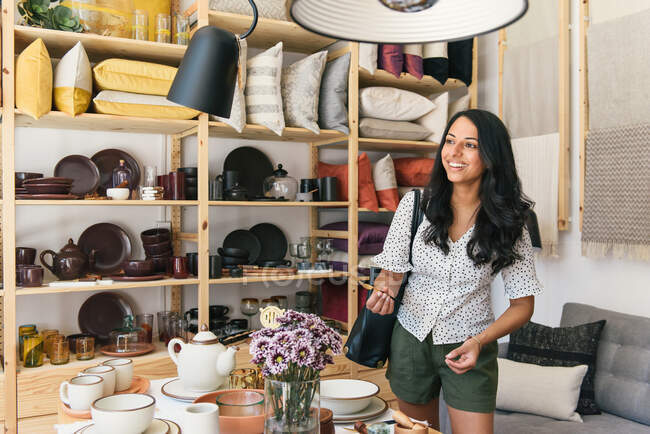 Adult woman smiling and picking up home goods while shopping — Stock Photo