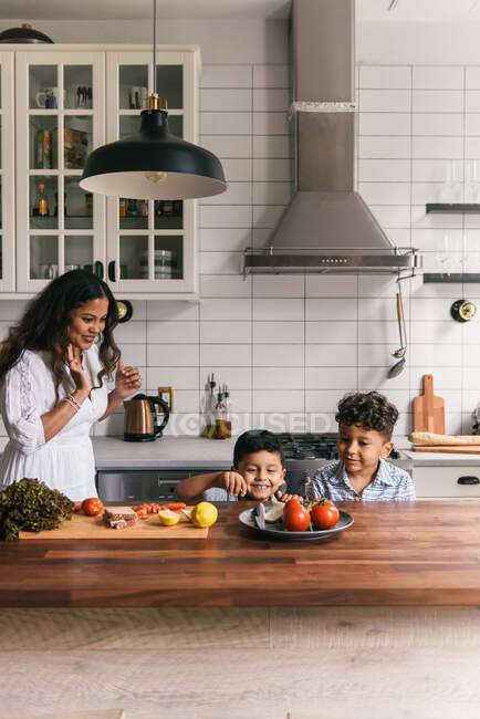Mother helping two young sons put together lunch at kitchen counter — Stock Photo