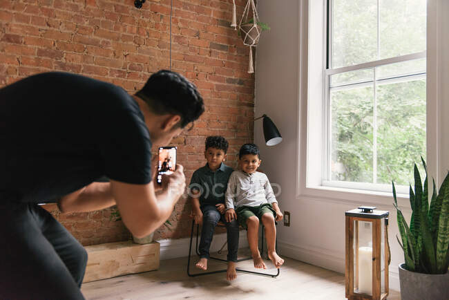 Dad taking phone photos of sons in stylish living room at home — Stock Photo