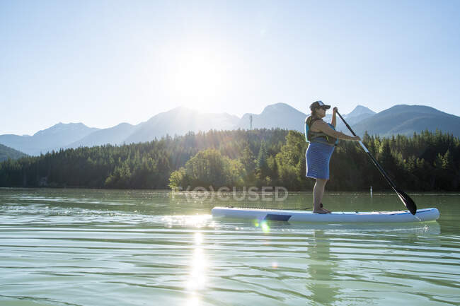 Беременная женщина катается на вёслах по озеру в горах — стоковое фото