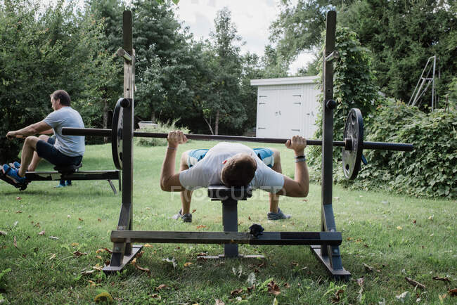 Dos hombres haciendo ejercicio en el jardín en su gimnasio en casa - foto de stock