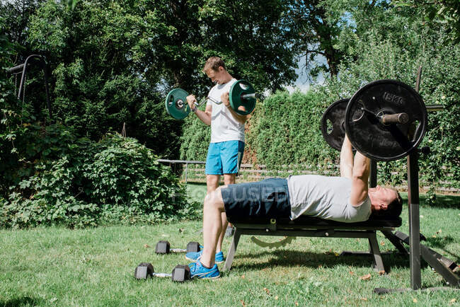 Dos hombres trabajando juntos en un gimnasio en casa en el jardín - foto de stock