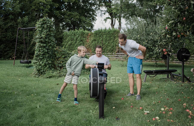 Due uomini e loro figlio che si allenano nella loro palestra di casa in giardino — Foto stock